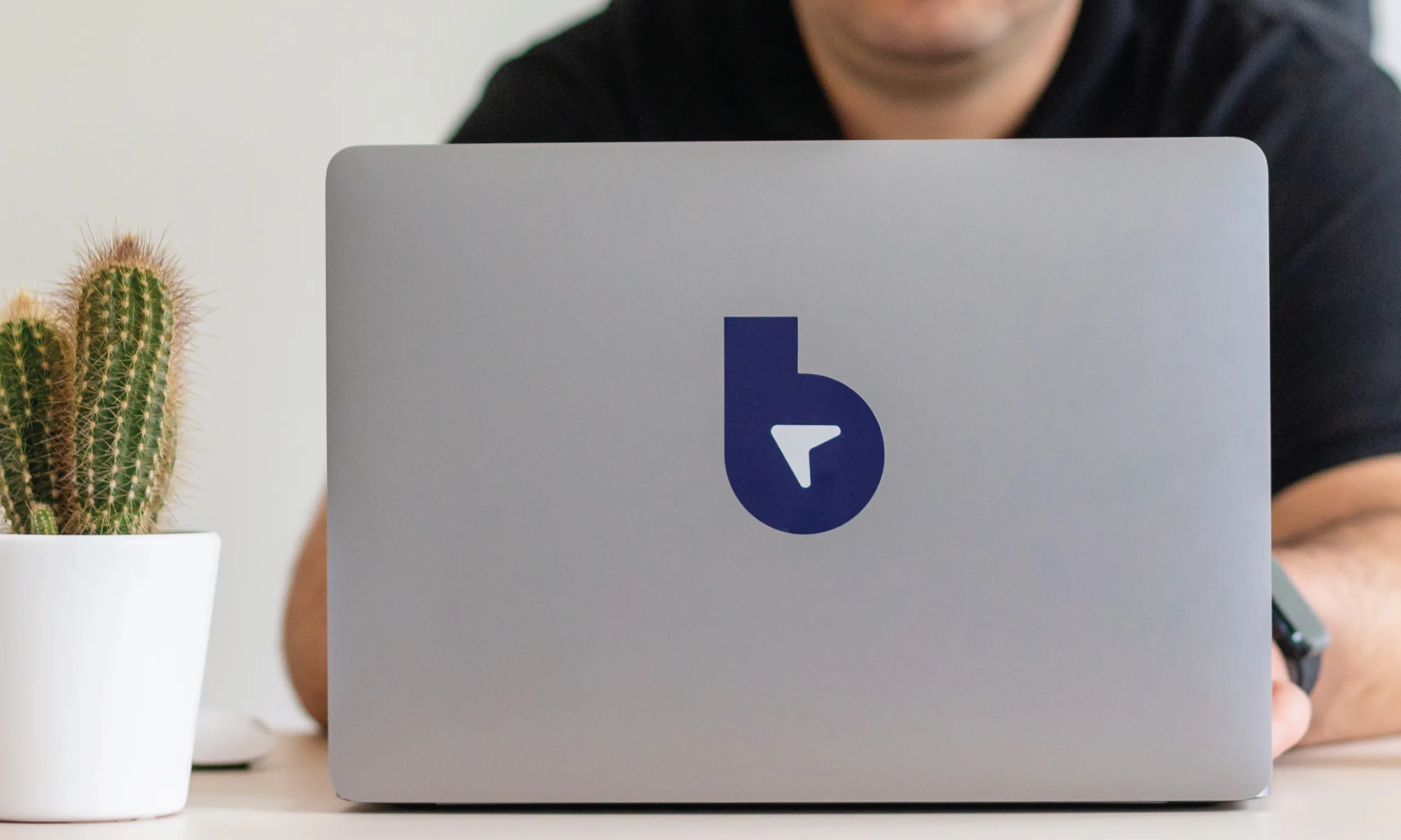 A closeup of a MacBook with a Lobbster logo next to cactus and a B2B eCommerce specialist behind the laptop.
