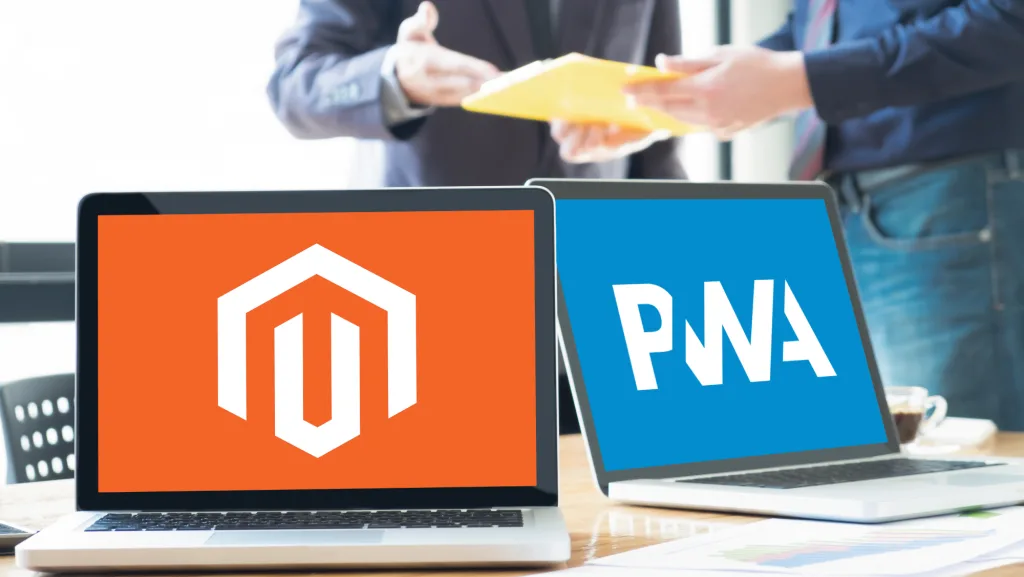 Magento and PWA logo displayed on two laptops and two man having a business meeting in the background. 
